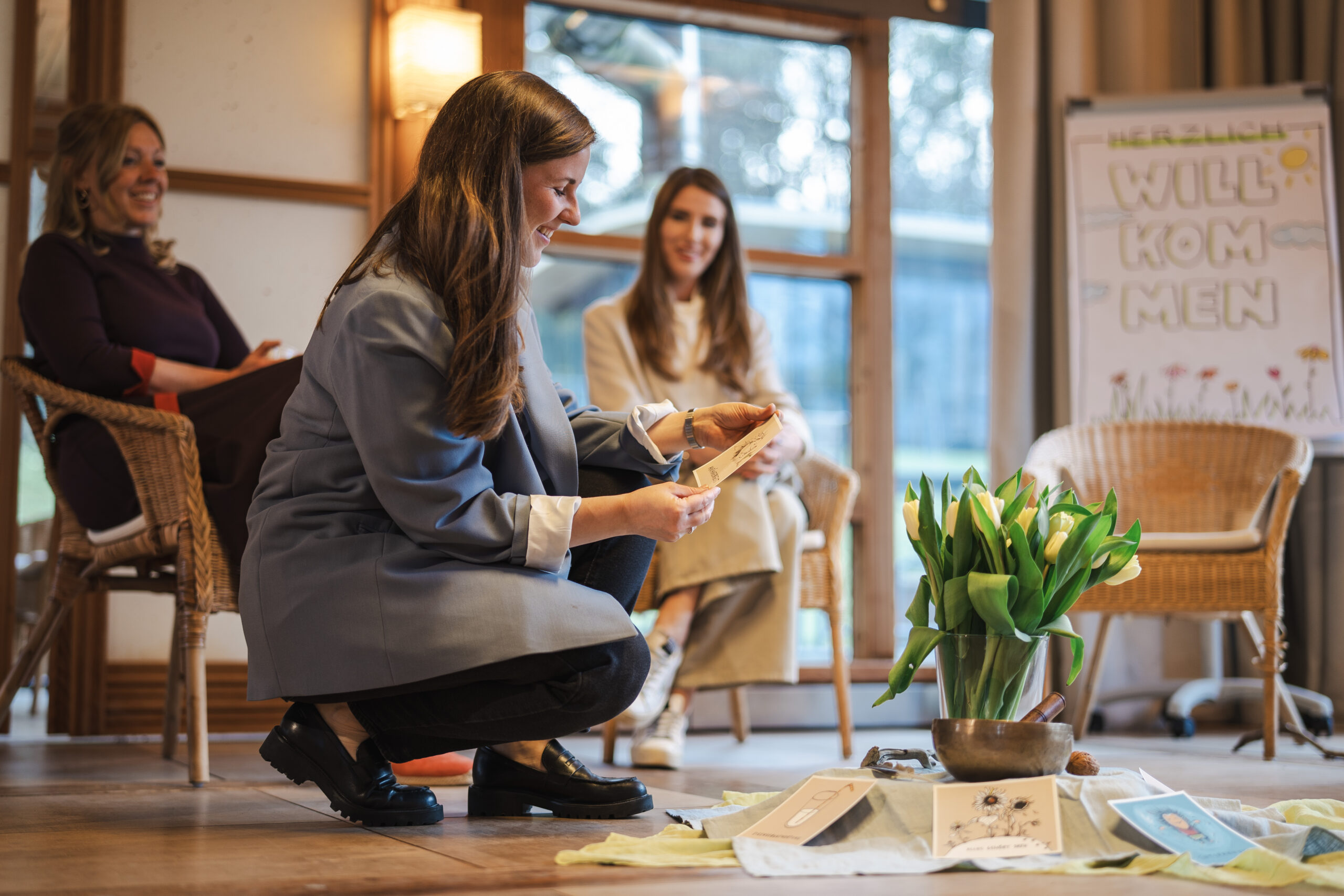 Eine Gruppe von Frauen bei einer Framechangers™ Vertrauensveranstaltung, eine liest eine Karte für ganzheitliche Führungskräfte.