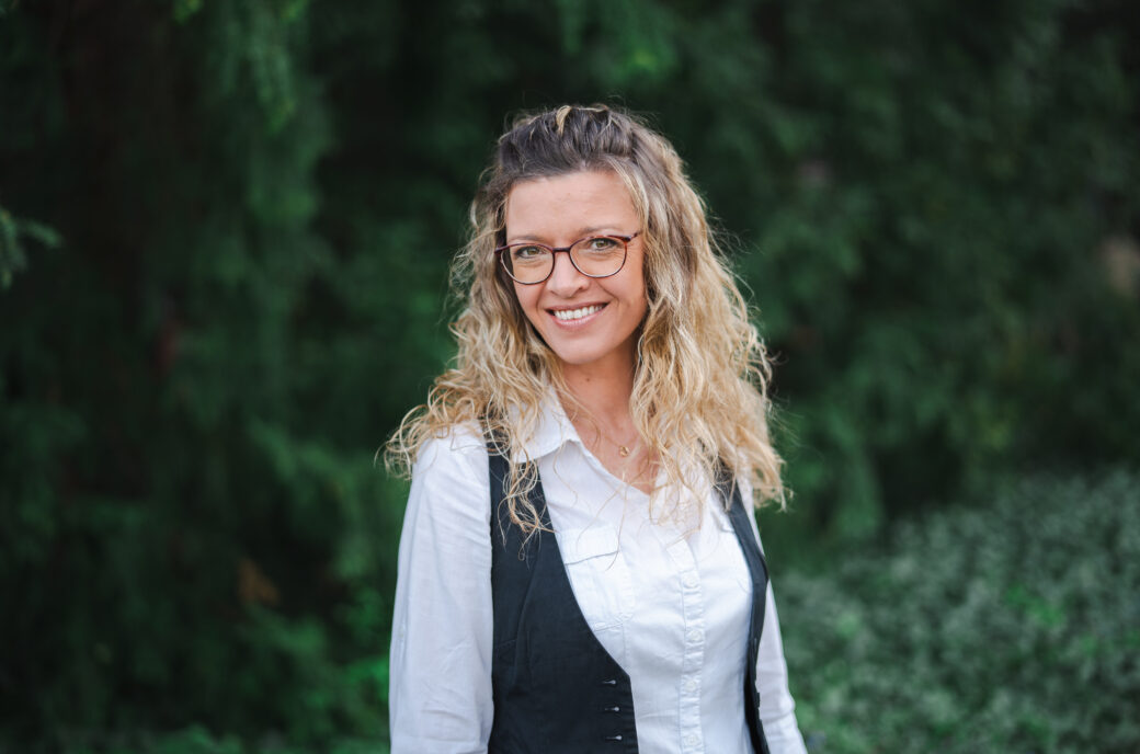 Mindful-Leadership-Coach Marion von Framechangers™ lächelt vor grünem Hintergrund.