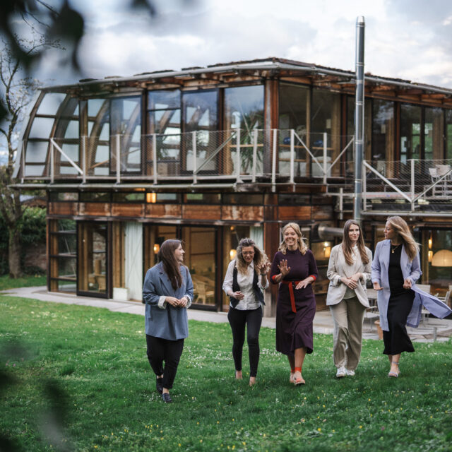 Fünf Business-Coaches vor einem modernen Haus im Gespräch.