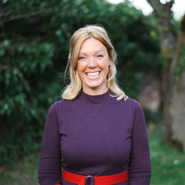 Steffi Fieber-Grandits, Mindful-Leadership-Coach und Framechangerin, lächelt vor grünem Hintergrund.