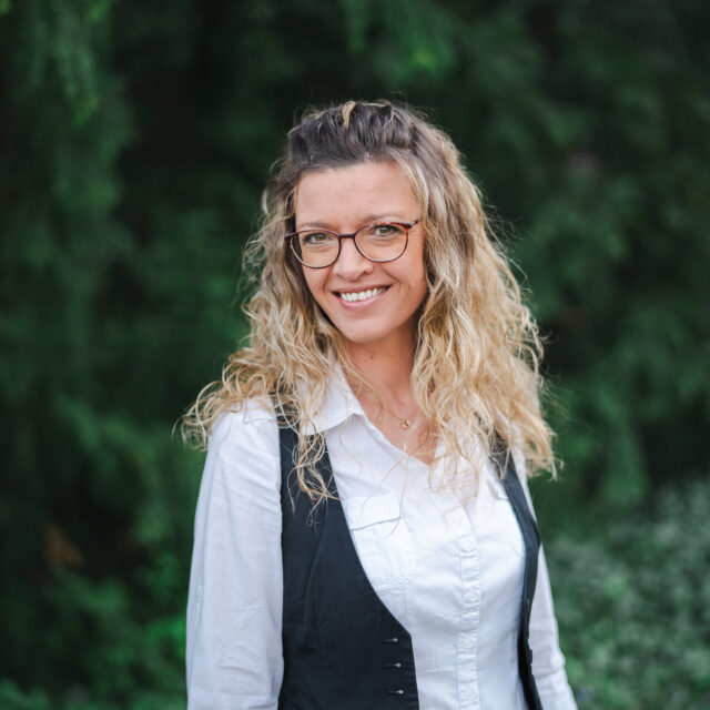 Marion, ein achtsamer Leadership Coach, lächelt vor einem grünen Hintergrund, Berufung und Lebensweg.