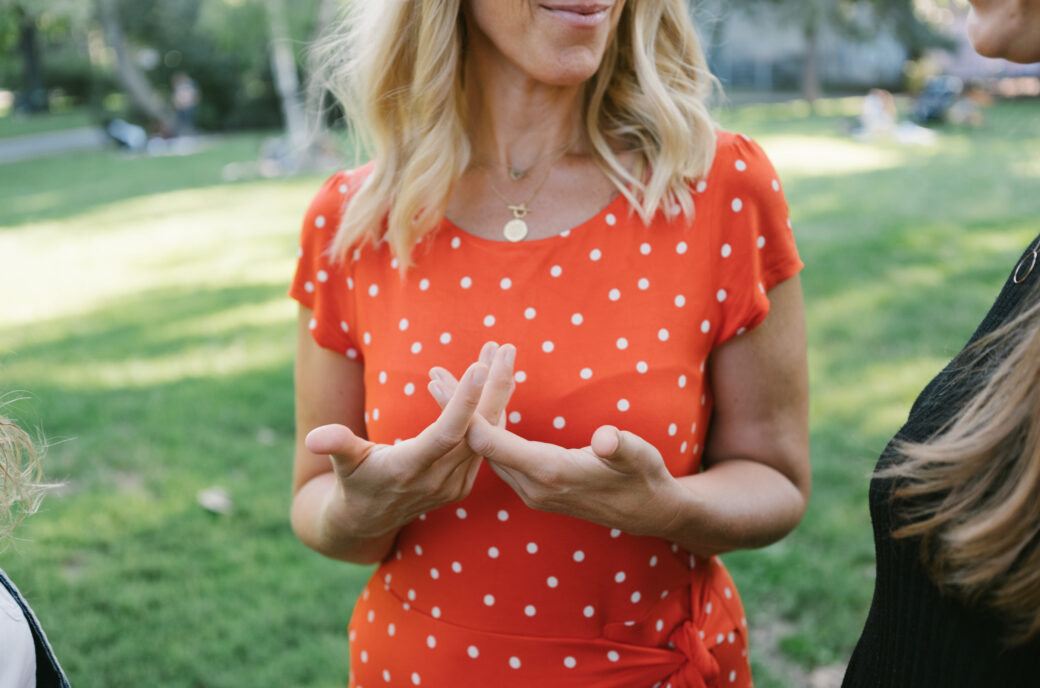 Frau im gepunkteten Kleid, die eine Geste der Achtsamkeit für Inside Out Leadership Coaching macht.