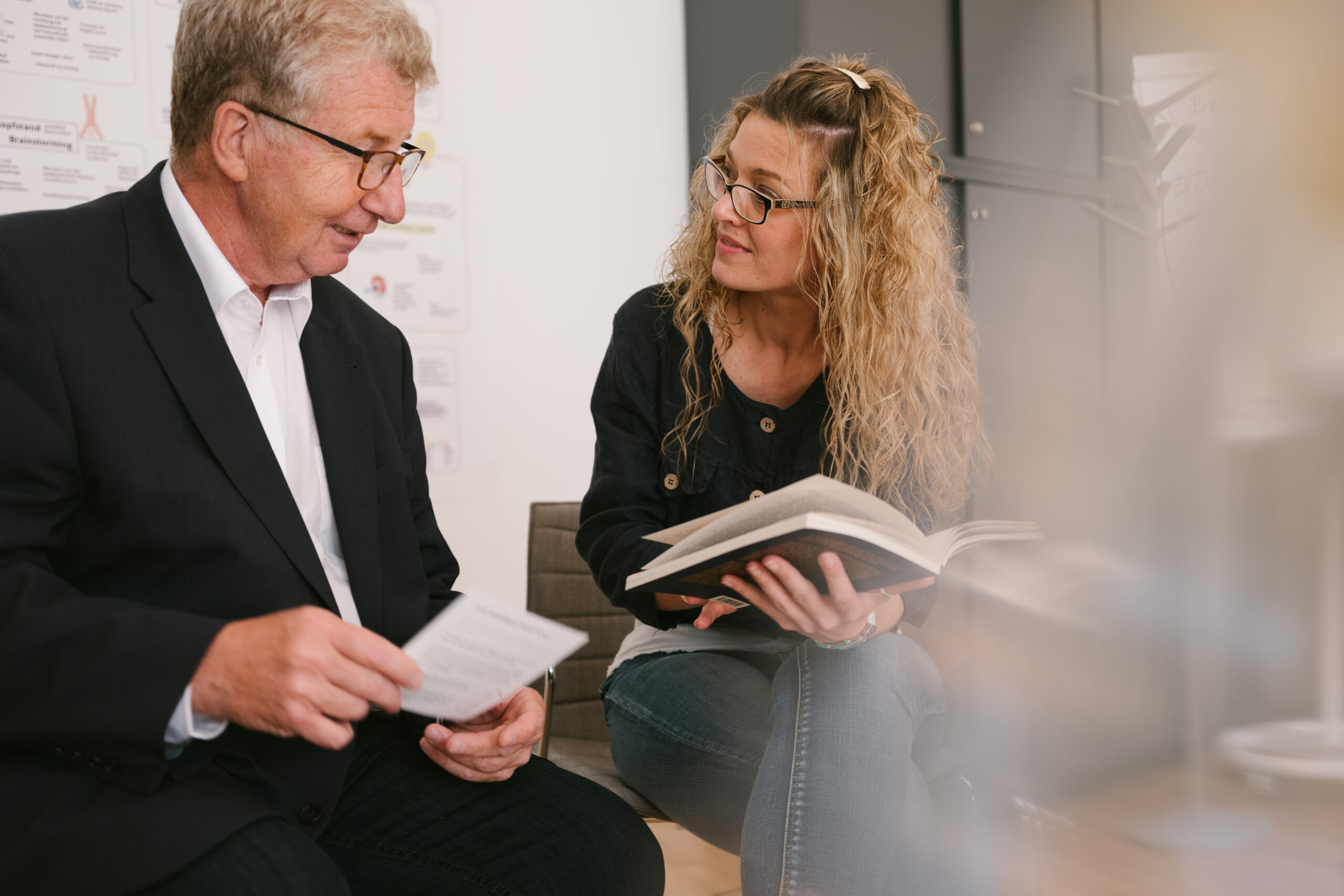 Ein Mann im Anzug und eine Frau mit Buch diskutieren im Rahmen des INSIDEOUT Leadership Development Journey.