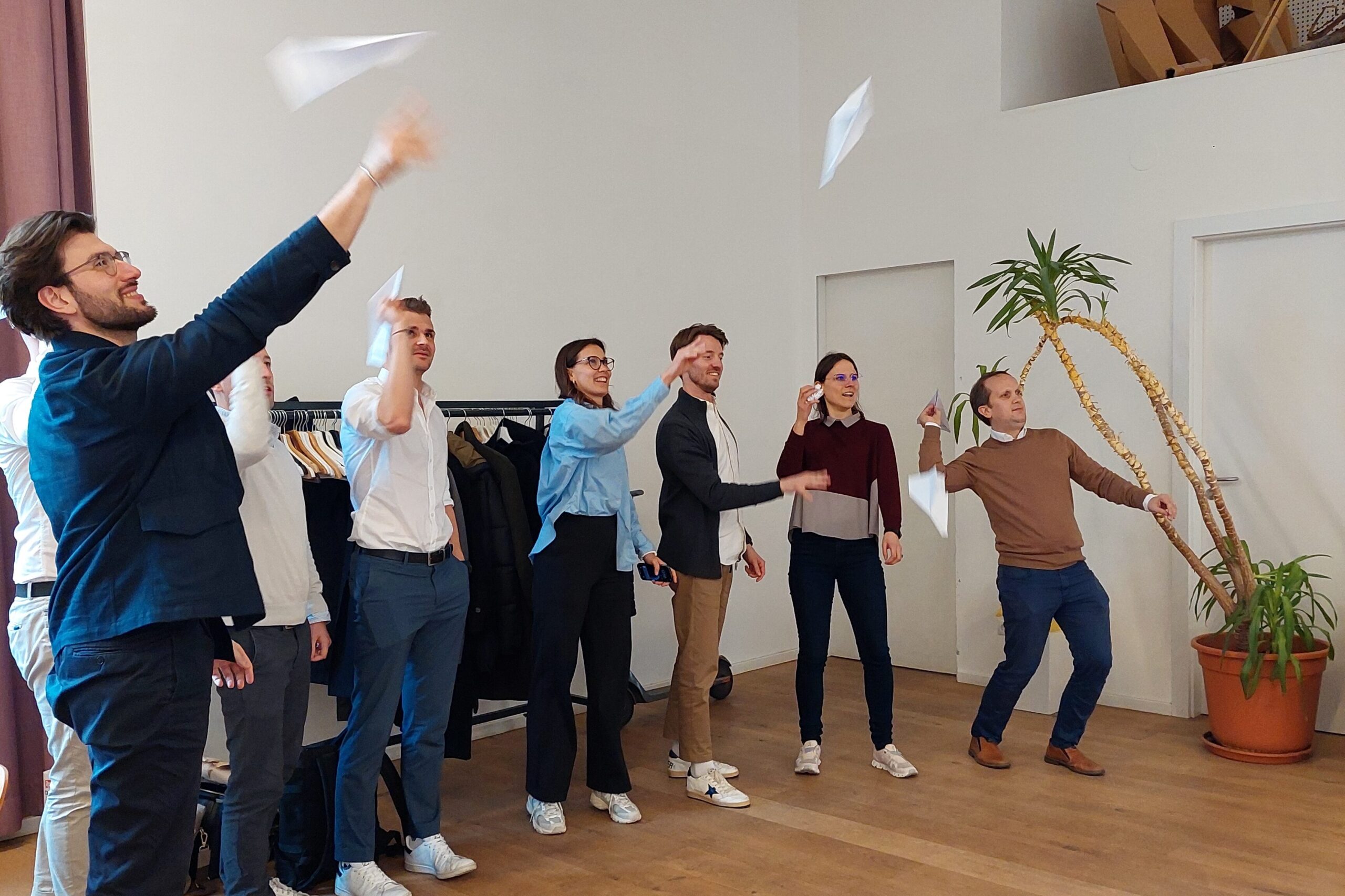 Eine Gruppe von Personen wirft während des SMART Leadership Trainings Papierflieger.