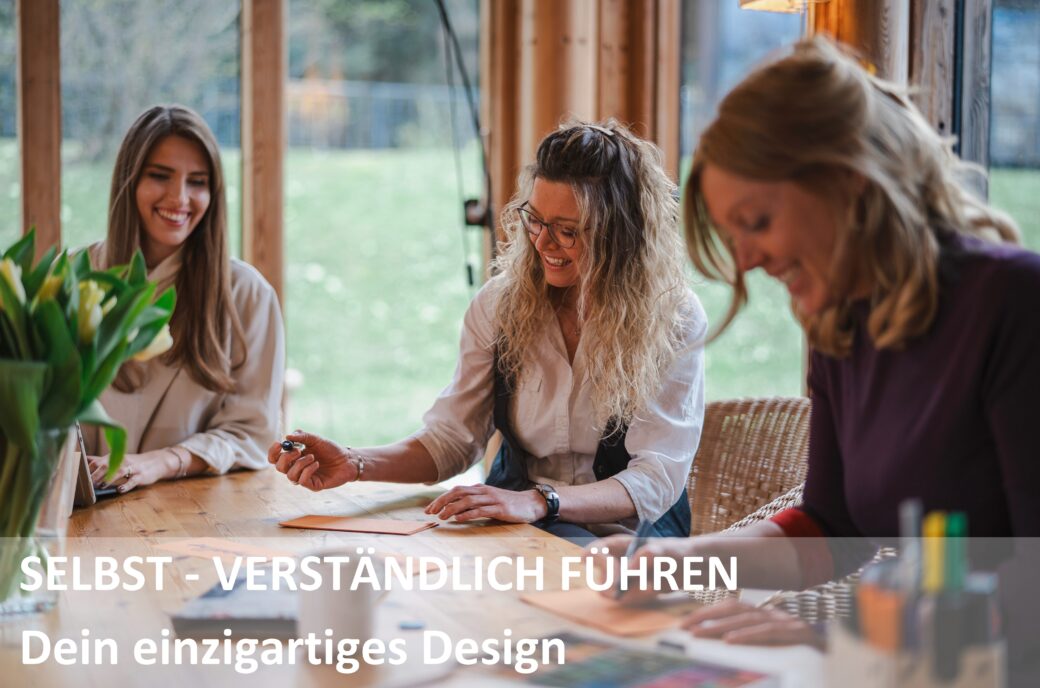 Drei lächelnde Frauen arbeiten gemeinsam an einem Tisch; Aufschrift auf das Bild: SELBST - VERSTÄNDLICH FÜHREN Dein einzigartiges Design