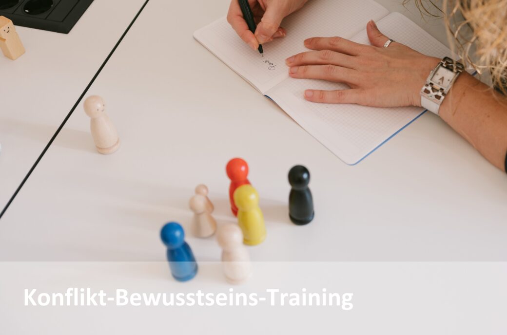 Frau schreibt in Notizbuch neben bunten Spielfiguren. Konflikt-Bewusstseins-Training