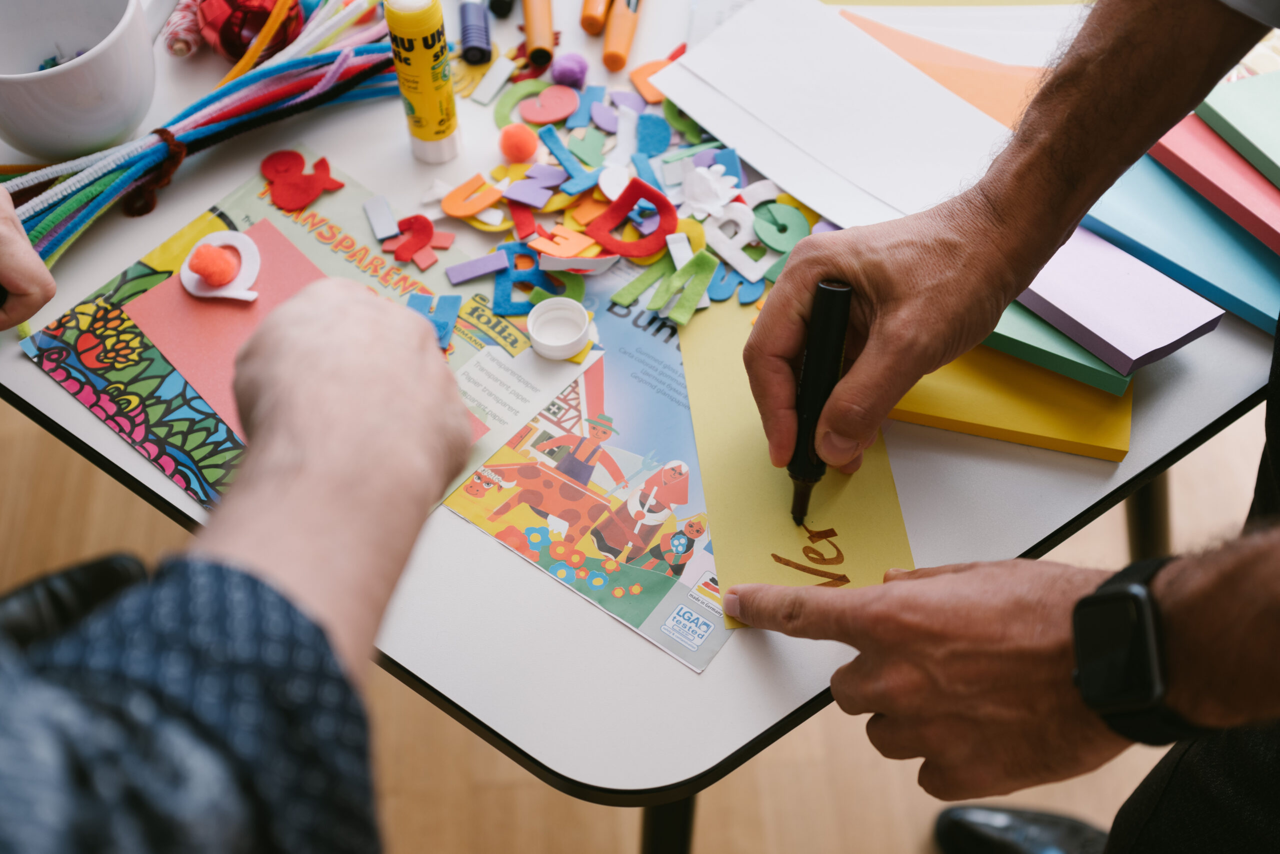 Personen, die an einem Tisch mit Bastelmaterialien arbeiten, Innovationsraum.