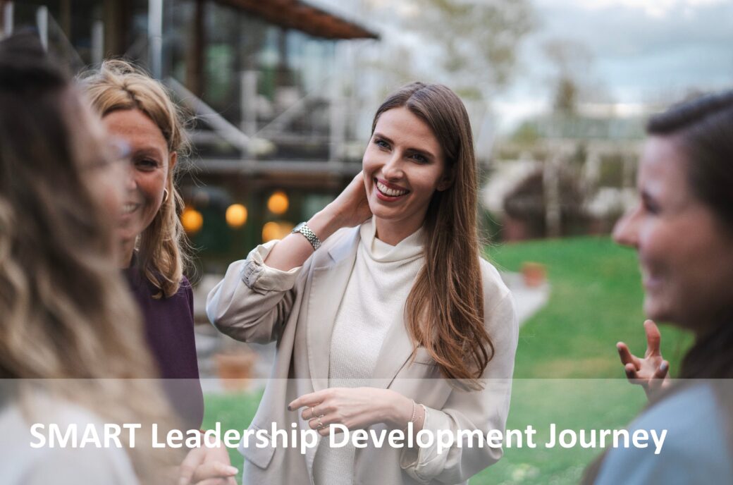 Eine lächelnde Frau, Teil einer Gruppe, im Gespräch über SMART Leadership Development.