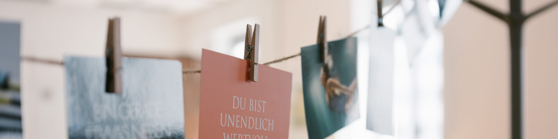 Persönliche Transformation einer Führungskraft Fallstudie: Fotos und Text „Du bist unendlich wertvoll“ hängen an einer Wäscheleine mit Wäscheklammern.