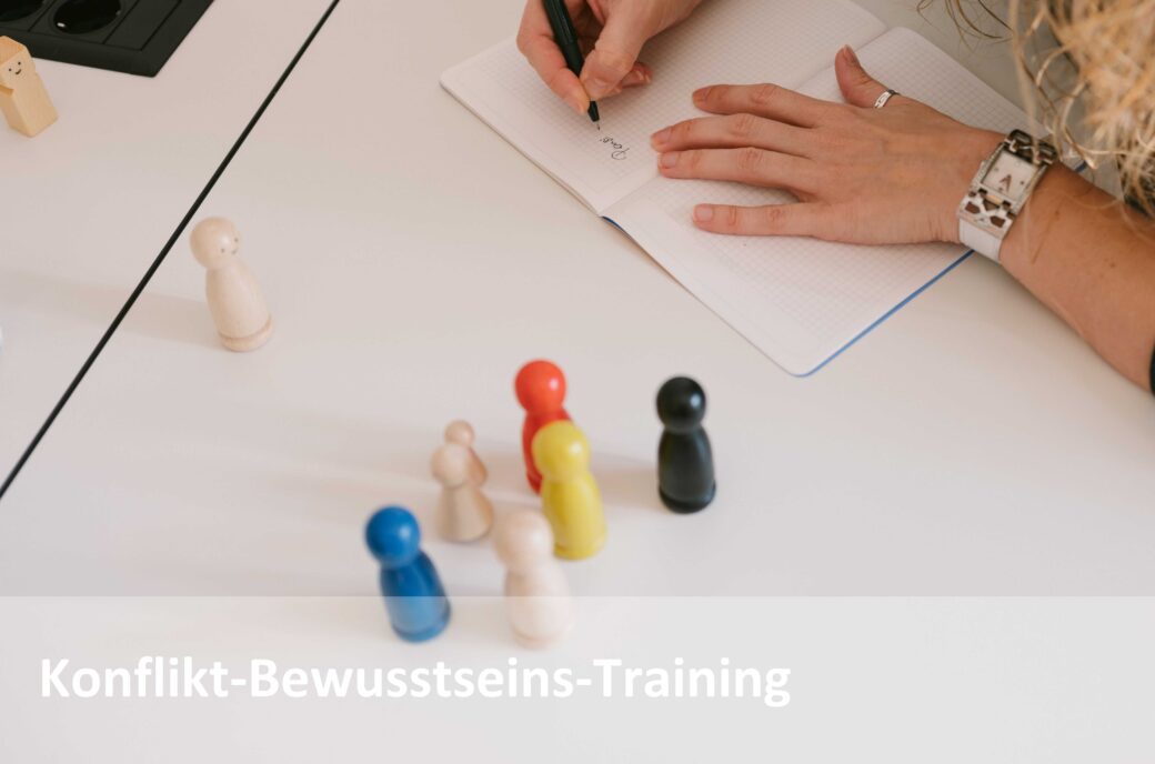 Frau schreibt Notizen neben bunten Spielfiguren; Text "Konflikt-Bewusstseins-Training"